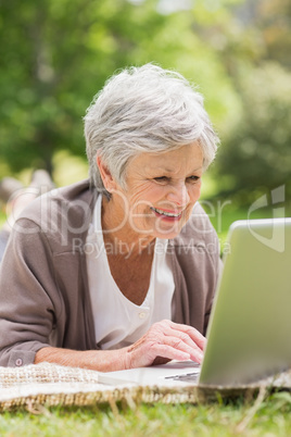 Smiling senior woman using laptop at park