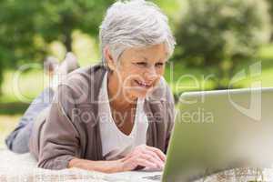 Smiling senior woman using laptop at park