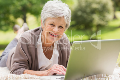 Smiling senior woman using laptop at park