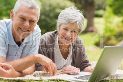 Smiling senior couple using laptop at park