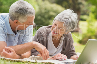 Smiling senior couple using laptop at park