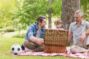 Grandfather, father and son with picnic basket