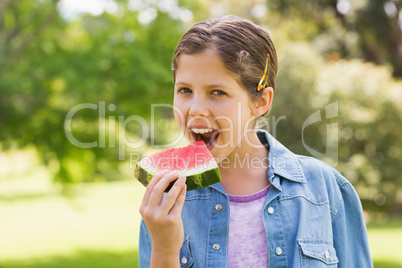 Smiling young girl eating water melon in park