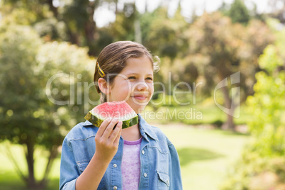 Smiling young girl eating water melon in park