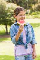 Smiling young girl eating water melon in park