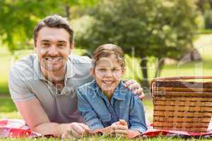 Smiling father with daughter lying on grass in park