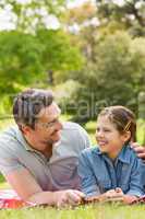 Father with young daughter lying on grass in park