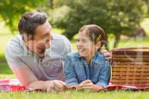 Smiling father with young daughter lying on grass in park