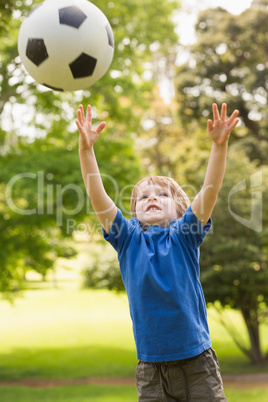 Smiling young boy playing with ball in park