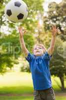 Smiling young boy playing with ball in park