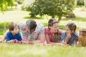 Smiling couple with young kids lying on grass in park