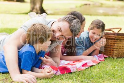 Smiling couple with young kids lying in park