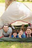 Couple with kids lying in the tent at park