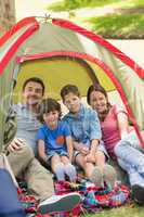 Couple with kids sitting in the tent at park