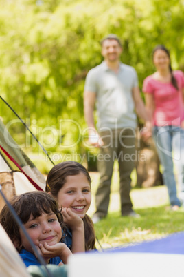 Kids in tent with couple in background at park