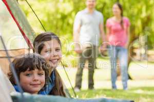 Kids in tent with couple in background at park