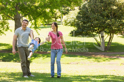 Family of three holding hands at park
