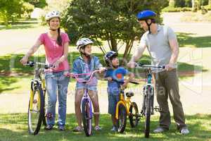 Family of four with bicycles in park