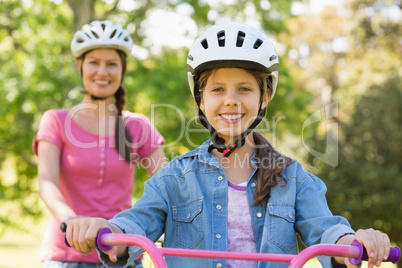 Smiling woman with her daughter riding a bicycle