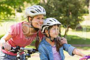Smiling woman with her daughter riding bicycles