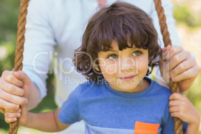 Close-up of a father pushing cute boy on swing