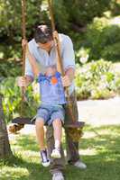 Happy father pushing boy on swing