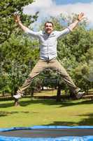 Happy man jumping high on trampoline in park