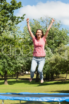 Happy woman jumping high on trampoline in park