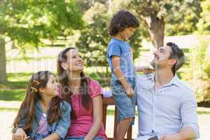 Couple with young kids sitting on park bench