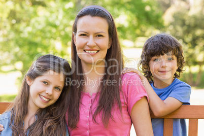 Smiling woman with kids sitting on park bench