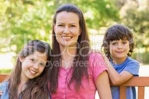 Smiling woman with kids sitting on park bench