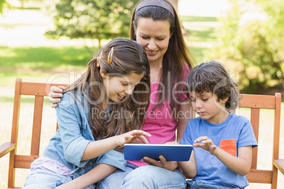 Woman with kids using digital tablet in park