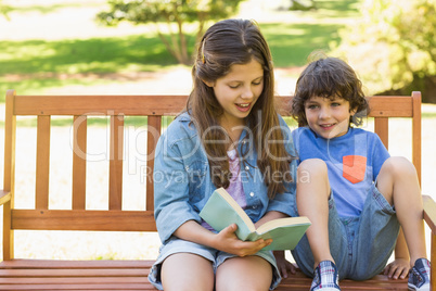 Kids reading book on park bench