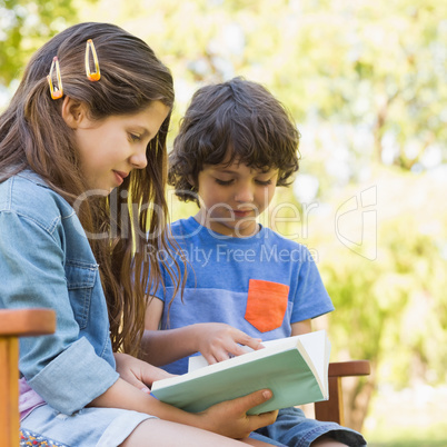 Side view of kids reading book on park bench