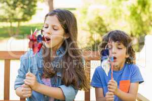 Kids blowing pinwheels on park bench