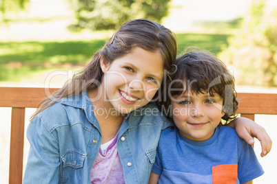 Portrait of cute kids sitting on park bench