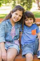 Young boy and girl sitting on park bench