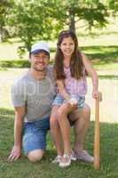 Father and daughter holding baseball bat in park