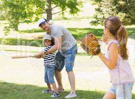 Family playing baseball in the park