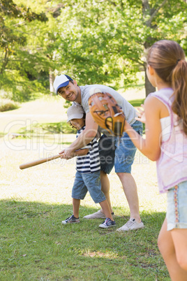 Family playing baseball in park