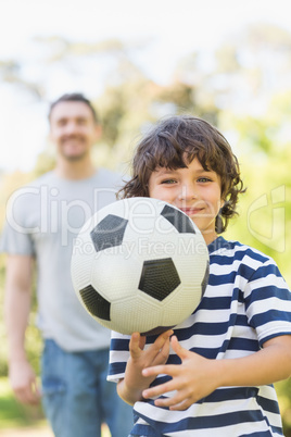 Father and son playing football in park