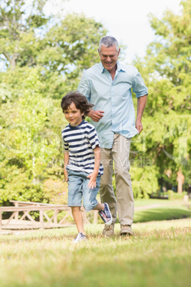 Grandfather and son running on grass in park