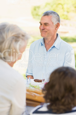 Senior man with family at outdoor dining table