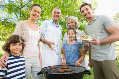 Extended family standing at barbecuing in park