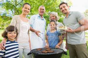 Extended family standing at barbecuing in park