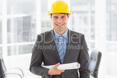 Happy architect holding blueprints smiling at camera