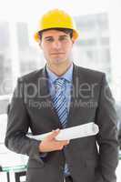 Happy architect holding blueprints looking at camera