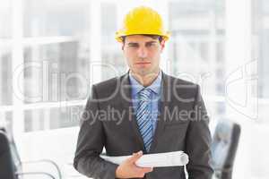Serious architect holding blueprints looking at camera