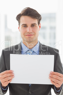 Smiling businessman holding blank page