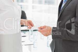 Businessman handing businesswoman a card